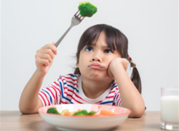 Young unhappy girl holding a piece of broccoli over her head