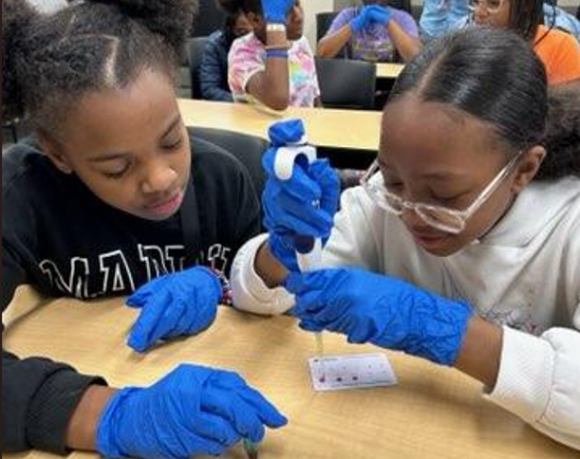 Two female students practicing using a micropipette