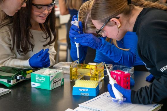 Students looking down at biotech lab equipment